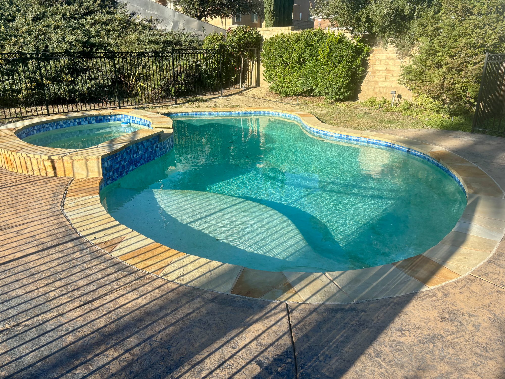 Freeform pool with spa and blue tile